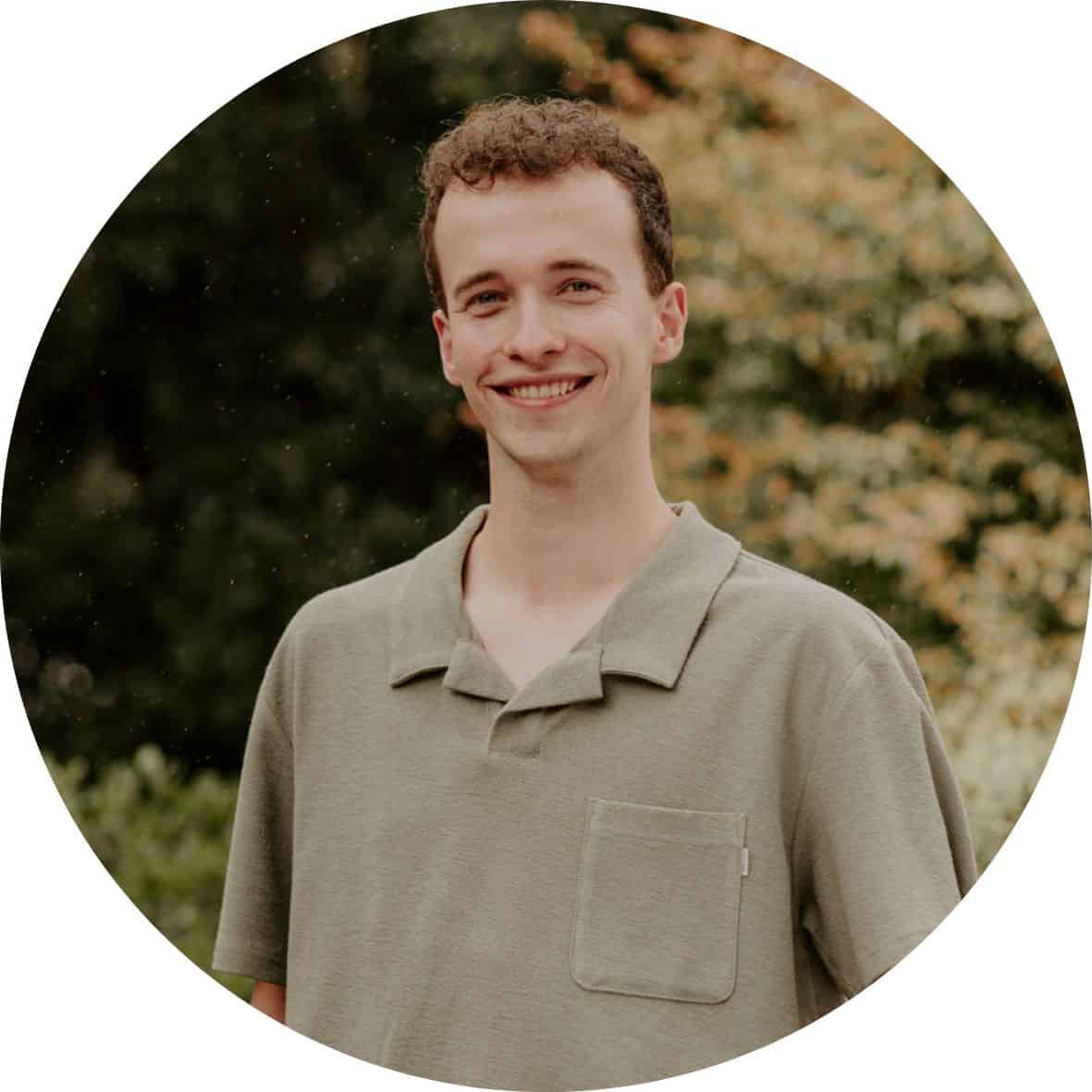Ryan Walker is wearing a green shirt and standing in front of trees