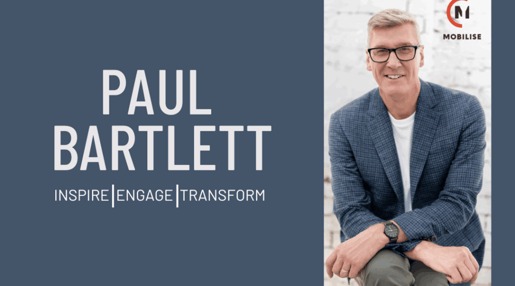 Image of a man in his sixties wearing black glasses and a blue and grey suit.