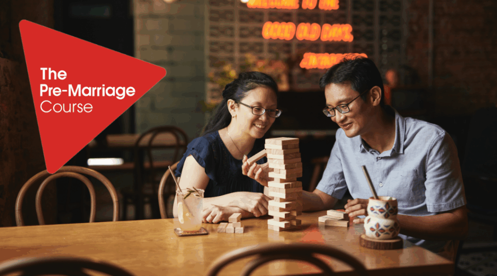 Asian man and women sitting at a table playing boad games