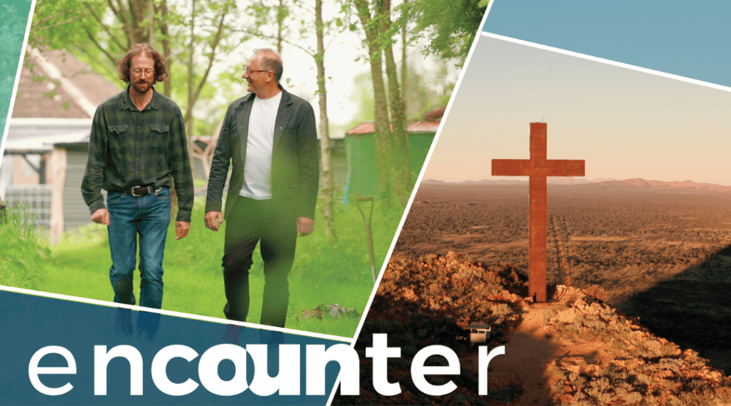 Karl and a man walking in a paddock. Rusty large cross standing on a mountain in Australia. Title: Encounter.