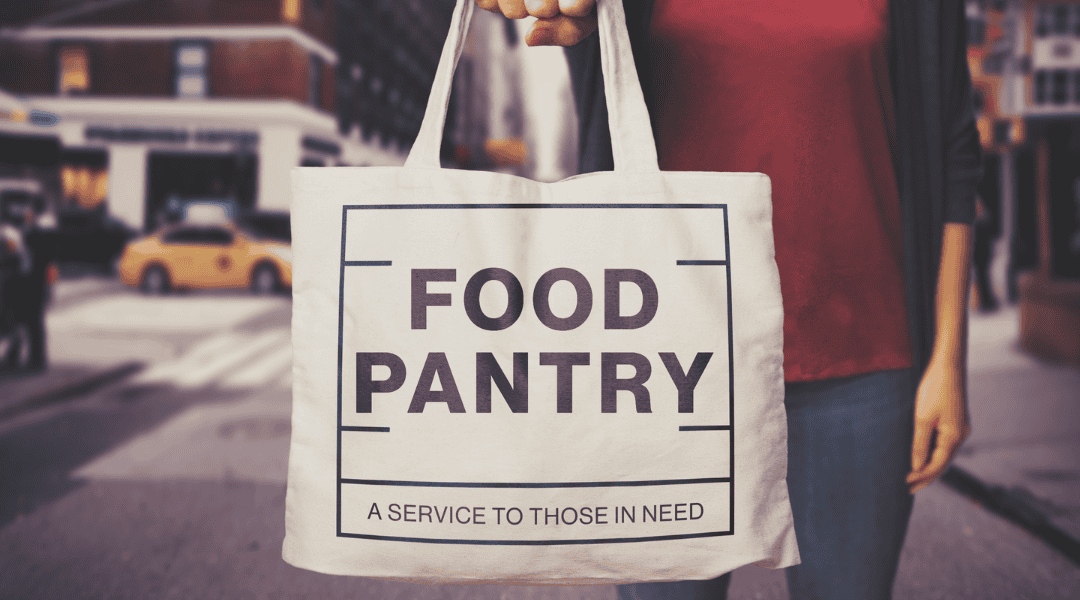 Lady carrying a large calico bag with Food Pantry written on the bag