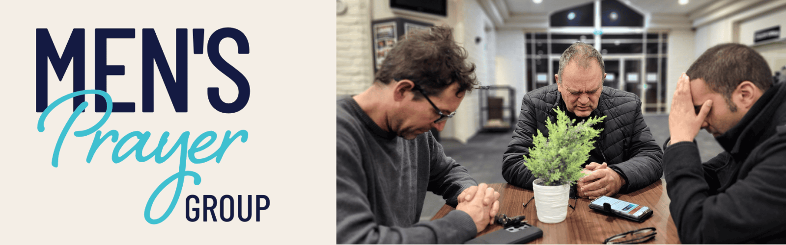 Men's Prayer Group. Photo of three men praying at a timber table with a plant in the centre.