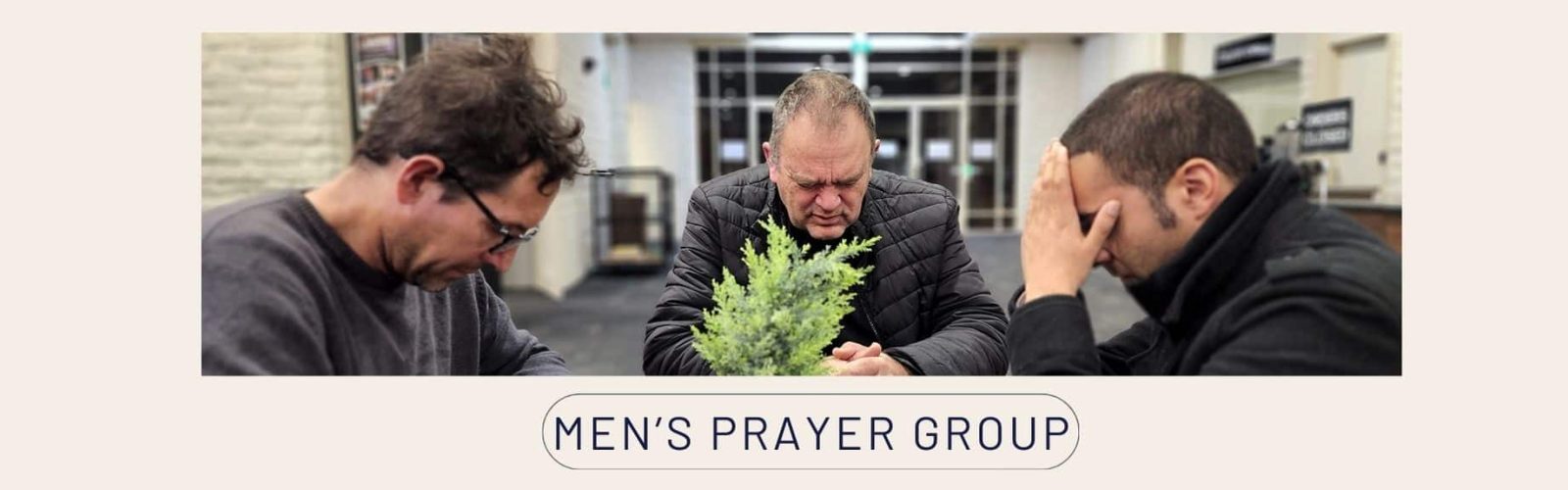 Image of three men praying at a table. Men's Prayer Group.