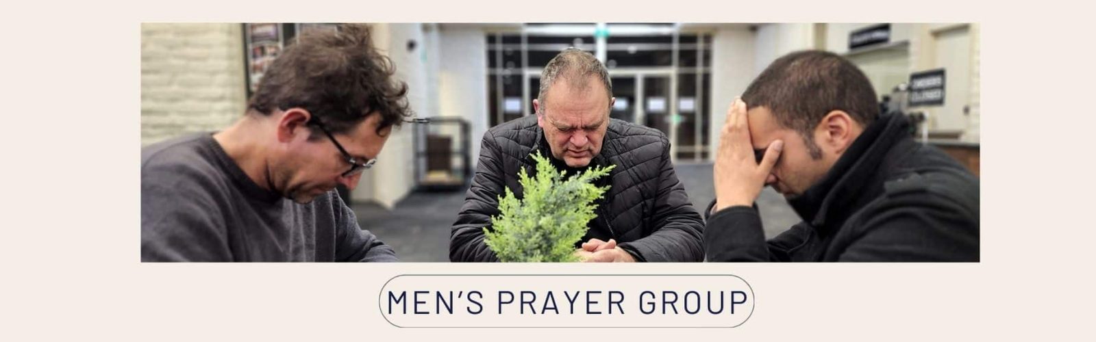 Image of three men praying at a table. Men's Prayer Group.