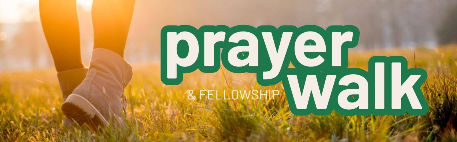 Image of a person wearing walking boots walking on grass with bush in the background