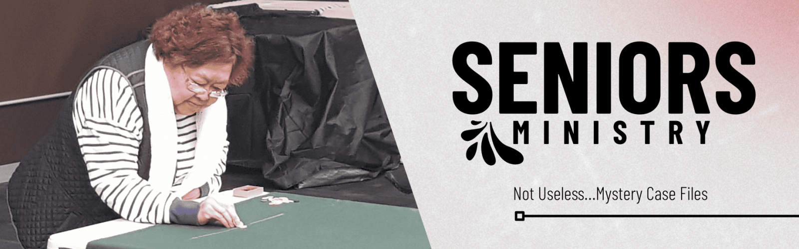 Image of a senior citizen inside playing a table game wearing a black and white striped top and black vest.